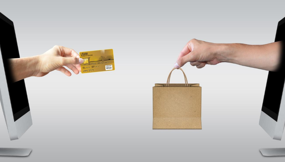 Hand with credit card, hand with brown shopping bag coming out of computer screens