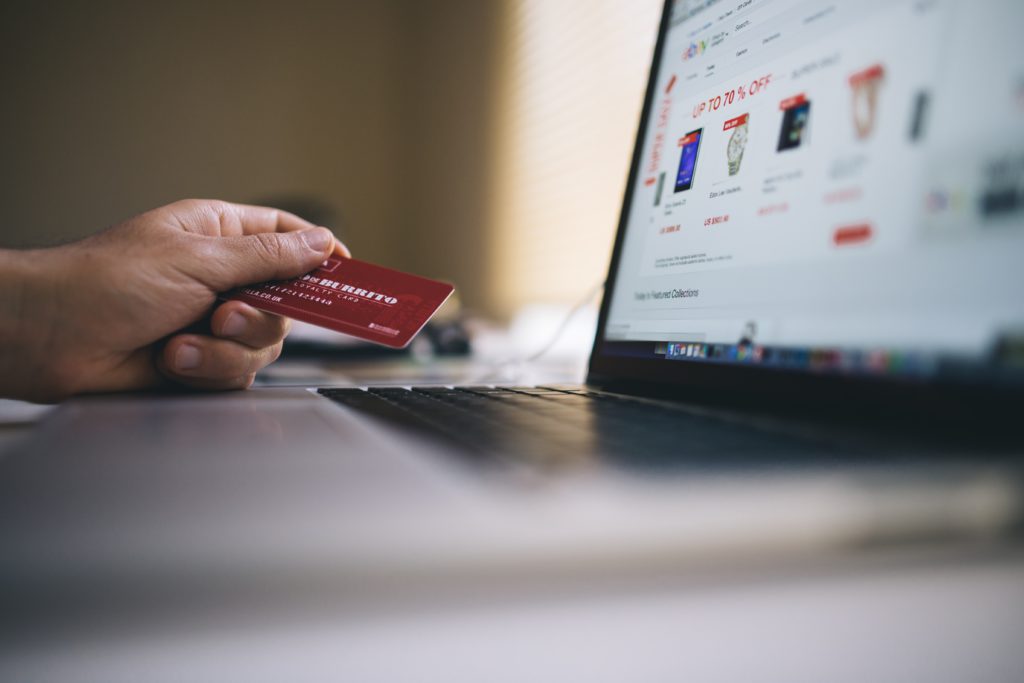 Person holding a card while shopping online using a laptop